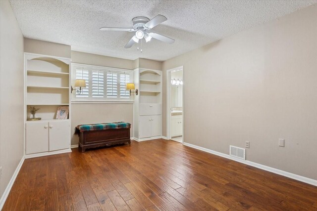 interior space with a textured ceiling, built in shelves, hardwood / wood-style floors, and ceiling fan