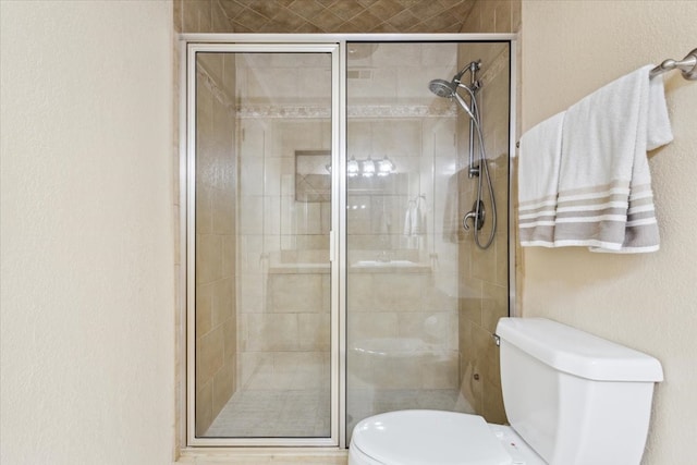 bathroom with a shower with door and toilet