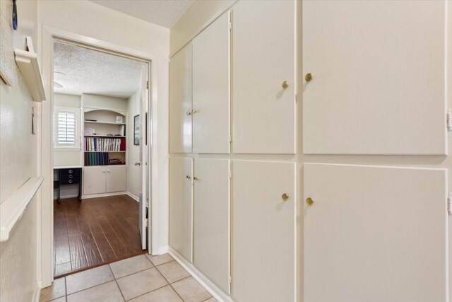 hall featuring a textured ceiling and light tile patterned floors