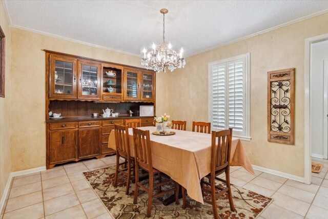 dining area featuring a notable chandelier, light tile patterned floors, and crown molding