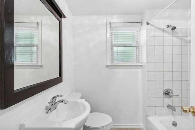 bathroom featuring toilet, plenty of natural light, and tiled shower / bath combo