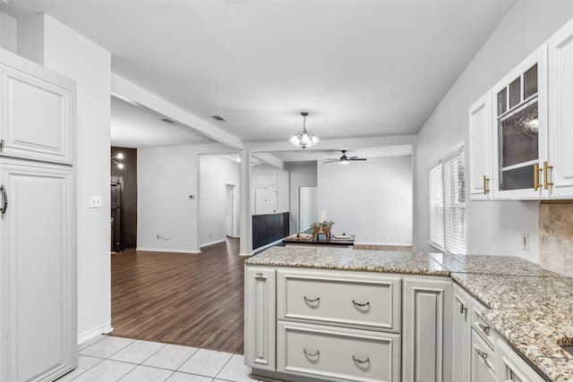 kitchen featuring kitchen peninsula, light tile patterned flooring, white cabinets, and ceiling fan