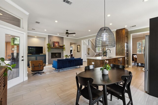 dining area with a high end fireplace, crown molding, sink, and ceiling fan