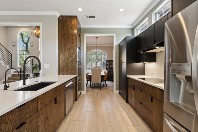 kitchen featuring stainless steel appliances, an inviting chandelier, crown molding, and sink