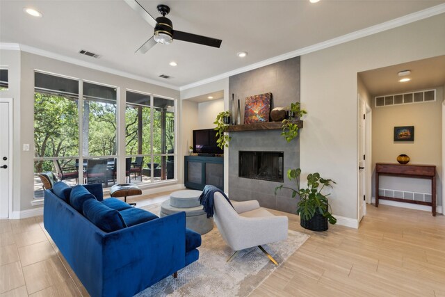 living room with ceiling fan, a wealth of natural light, a fireplace, and crown molding