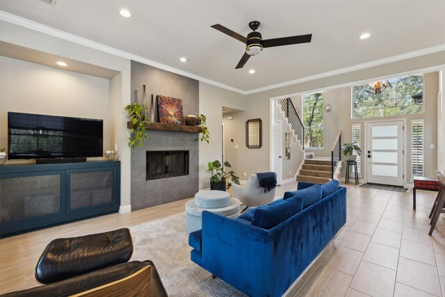 living room featuring a fireplace, ornamental molding, ceiling fan, and tile patterned floors