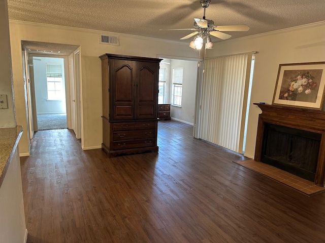 living room featuring visible vents, ornamental molding, dark wood-type flooring, a textured ceiling, and a fireplace