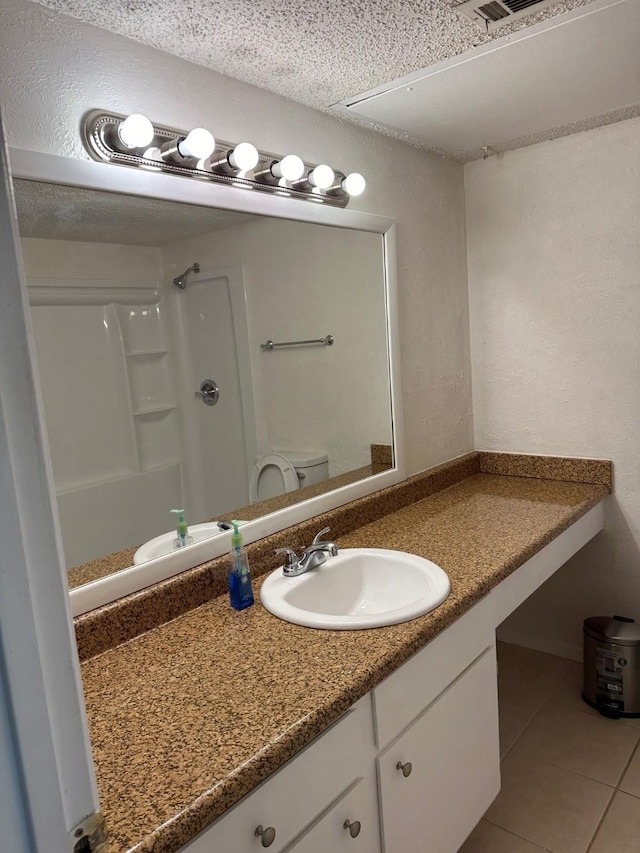 bathroom featuring toilet, vanity, walk in shower, and tile patterned floors