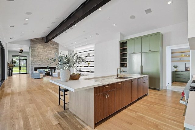 kitchen with lofted ceiling with beams, sink, a large island, green cabinetry, and light hardwood / wood-style flooring