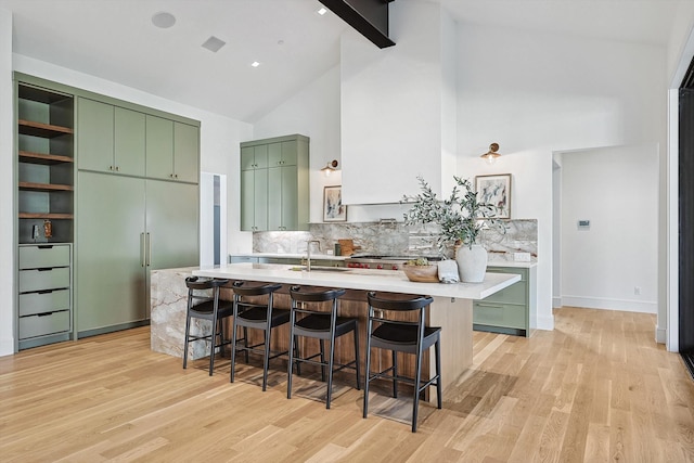 kitchen with open shelves, green cabinetry, light countertops, light wood-style flooring, and a sink