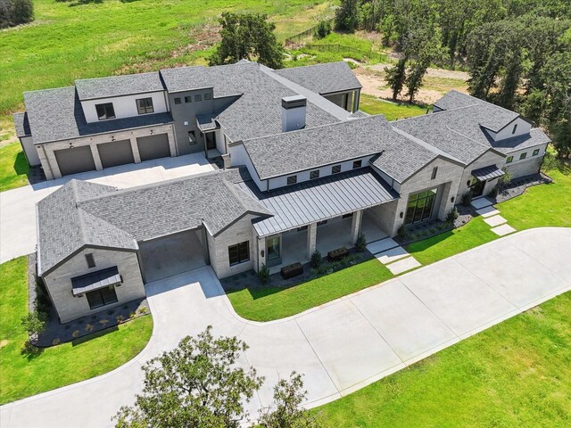 contemporary house with driveway, stone siding, and a front yard