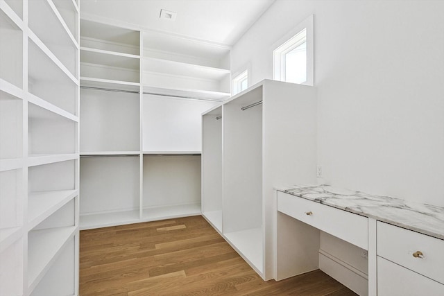 spacious closet featuring built in desk and hardwood / wood-style floors