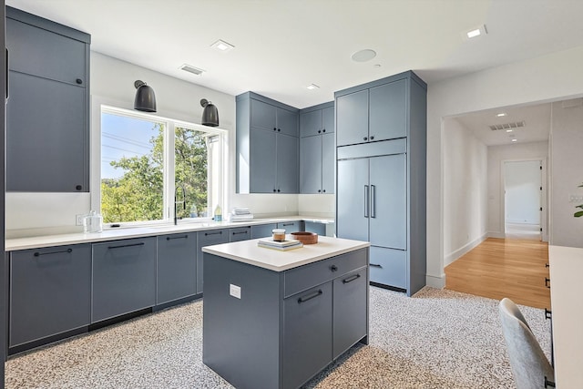 kitchen featuring paneled built in refrigerator, sink, and a kitchen island