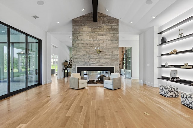 unfurnished living room featuring high vaulted ceiling, a fireplace, beamed ceiling, and light hardwood / wood-style floors