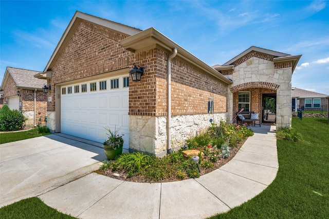 french provincial home with a garage, driveway, stone siding, a front lawn, and brick siding