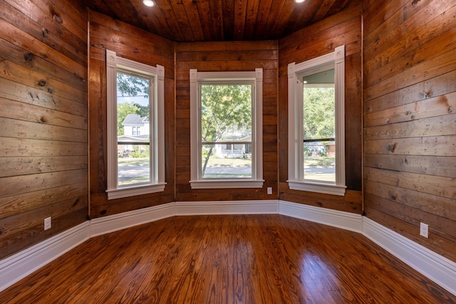 spare room featuring wood walls, plenty of natural light, and hardwood / wood-style floors