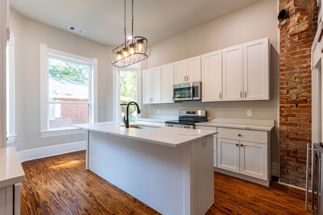 kitchen with dark hardwood / wood-style flooring, a center island with sink, decorative light fixtures, stainless steel appliances, and sink