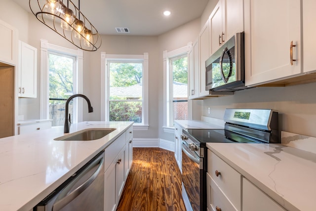 kitchen featuring appliances with stainless steel finishes, light stone counters, dark hardwood / wood-style flooring, and sink