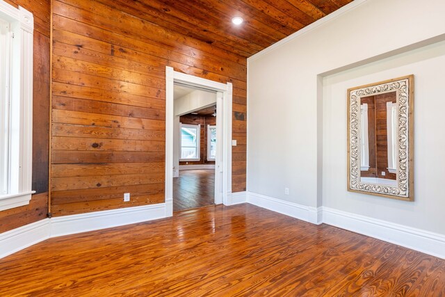 unfurnished room with crown molding, wooden walls, hardwood / wood-style floors, and wood ceiling