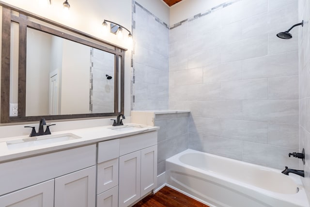 bathroom with hardwood / wood-style floors, tiled shower / bath, and double sink vanity