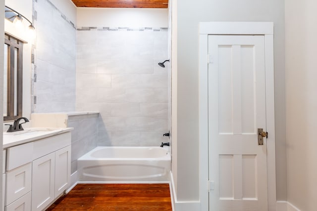 bathroom with tiled shower / bath combo, vanity, and wood-type flooring