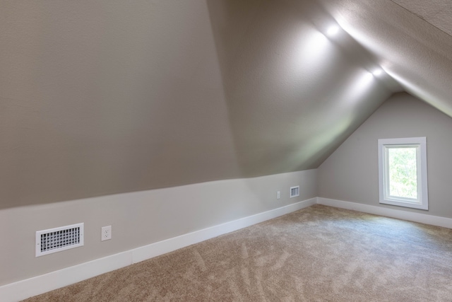 bonus room featuring a textured ceiling, vaulted ceiling, and carpet