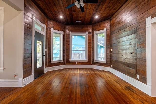 empty room featuring ceiling fan, wood-type flooring, wooden ceiling, and wooden walls