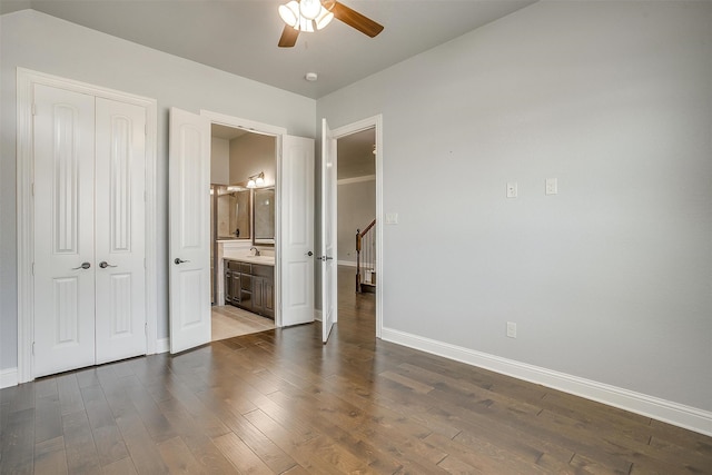 unfurnished bedroom featuring ceiling fan, sink, dark hardwood / wood-style flooring, and ensuite bathroom