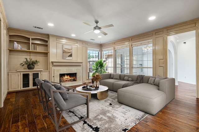 living room with dark wood-style flooring, visible vents, ceiling fan, and a premium fireplace