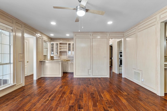 unfurnished living room featuring dark wood-style flooring, visible vents, ceiling fan, and a decorative wall