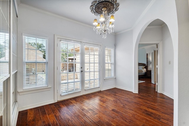 unfurnished dining area with baseboards, arched walkways, dark wood-style flooring, an inviting chandelier, and crown molding