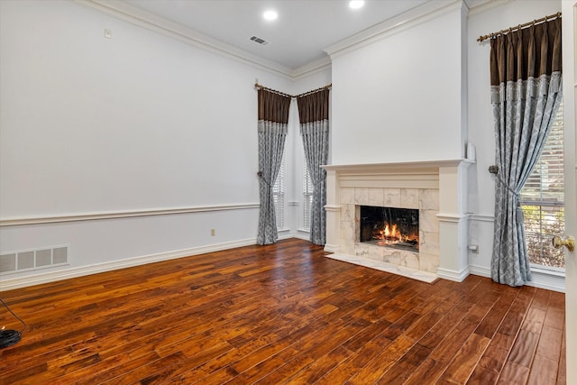 unfurnished living room with baseboards, a fireplace, visible vents, and crown molding