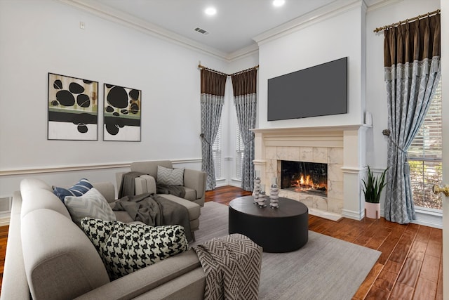 living area with crown molding, recessed lighting, visible vents, wood finished floors, and a tile fireplace