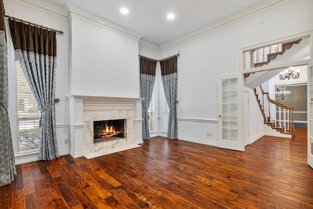 unfurnished living room with ornamental molding, a fireplace, wood finished floors, and a notable chandelier