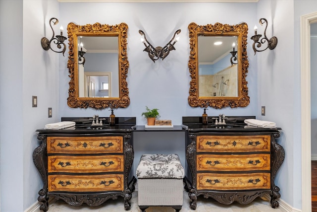 bathroom with a shower, two vanities, a sink, and baseboards