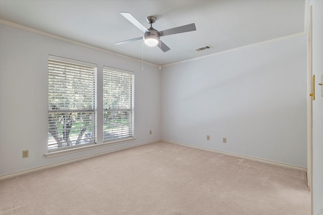 spare room with ornamental molding, a ceiling fan, visible vents, and light colored carpet