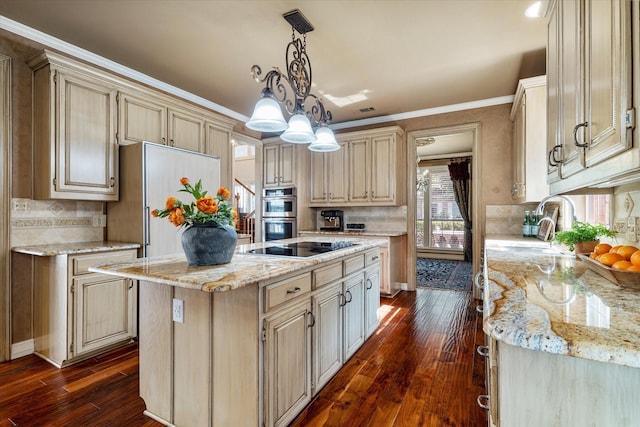 kitchen with double oven, a center island, cream cabinetry, light stone countertops, and decorative light fixtures