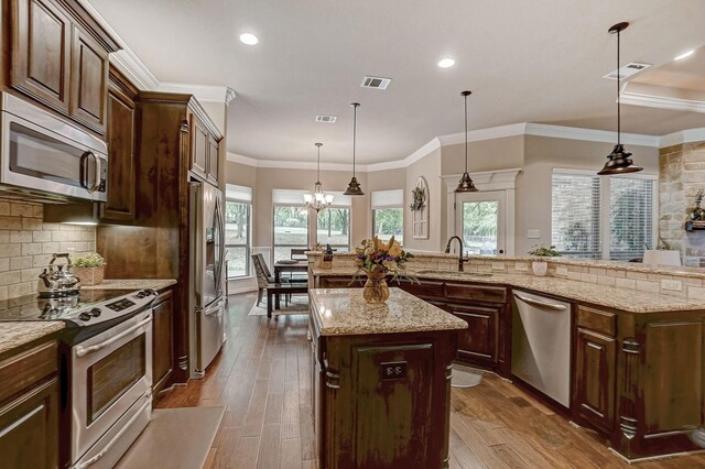 kitchen with ceiling fan, a kitchen island with sink, hardwood / wood-style flooring, stainless steel dishwasher, and sink