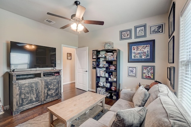 living room featuring dark wood-type flooring, ceiling fan, and a wealth of natural light