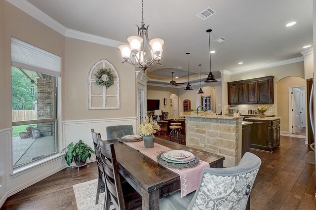 dining area featuring crown molding, ceiling fan with notable chandelier, and dark hardwood / wood-style floors