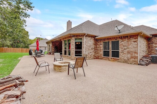 rear view of property with a lawn, a patio area, and an outdoor fire pit