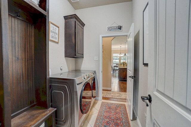 washroom with light tile patterned floors, washing machine and dryer, and cabinets