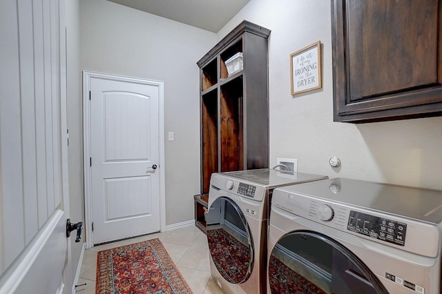 clothes washing area with light tile patterned floors, cabinets, and washing machine and clothes dryer