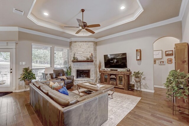 living room with light hardwood / wood-style flooring, a tray ceiling, crown molding, and ceiling fan