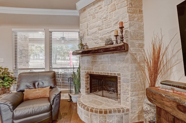 sitting room with a stone fireplace, hardwood / wood-style flooring, and crown molding