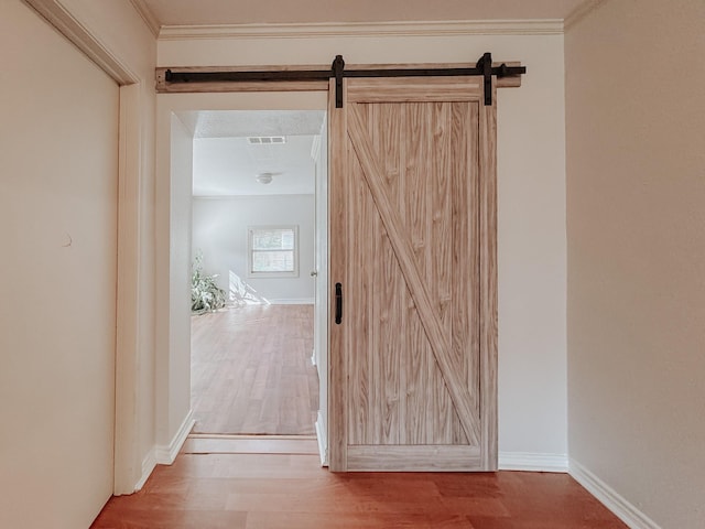 hall featuring hardwood / wood-style floors, crown molding, and a barn door