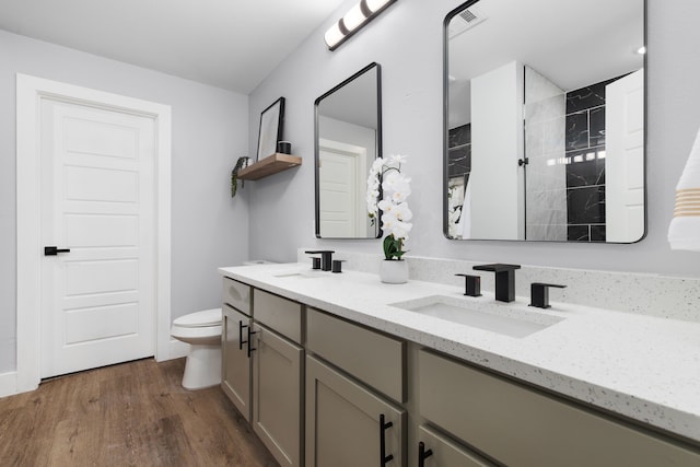 bathroom featuring double vanity, toilet, and hardwood / wood-style floors