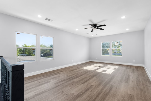 empty room with ceiling fan, a wealth of natural light, and light hardwood / wood-style floors