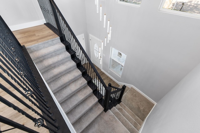 staircase with hardwood / wood-style floors and a high ceiling