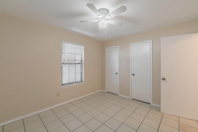 unfurnished bedroom featuring ceiling fan, two closets, and light tile patterned floors